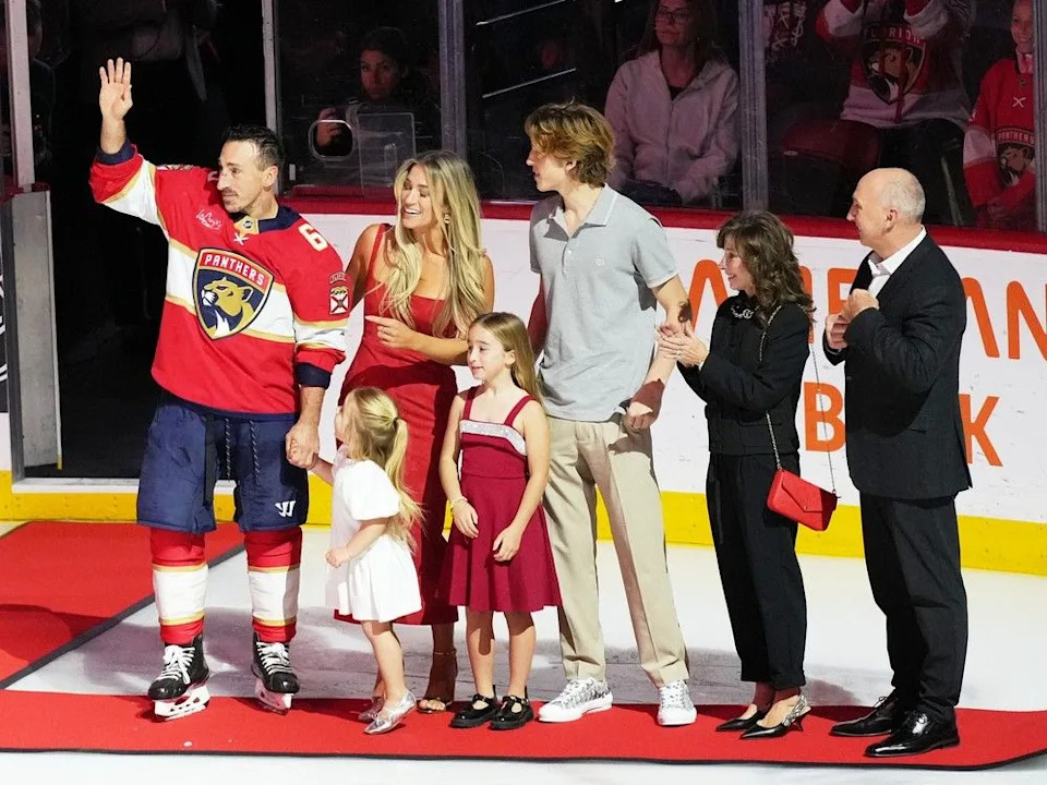  Florida Panthers left wing Brad Marchand, left, waves as he stands with family members as he is recognized for having reached 1,000 NHL points before an NHL hockey game between the Florida Panthers and the Montreal Canadiens, Tuesday, Dec. 30, 2025, in Sunrise, Fla.
