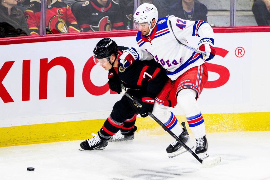 Ottawa Senators' Brady Tkachuk (7) fights off New York Rangers' Noah Laba (42) for possession of the puck.