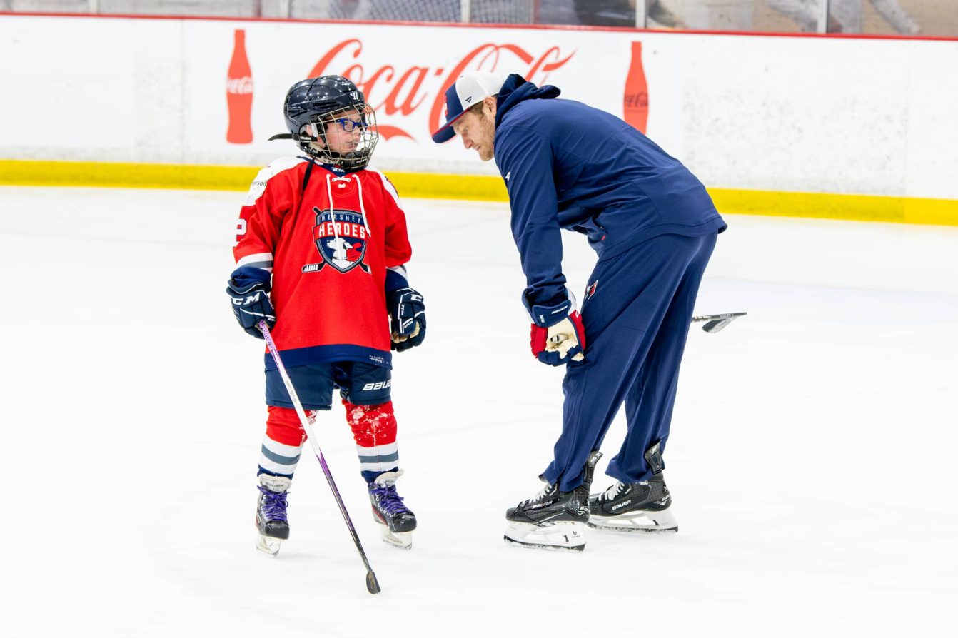 Ethen Frank listens to a child at the American Special Hockey Association clinic