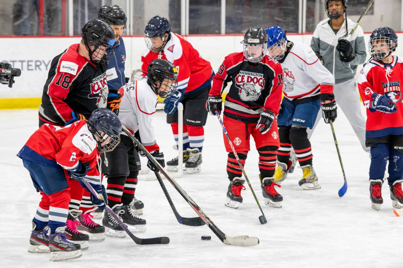 Players huddle around a puck at the American Special Hockey Association clinic