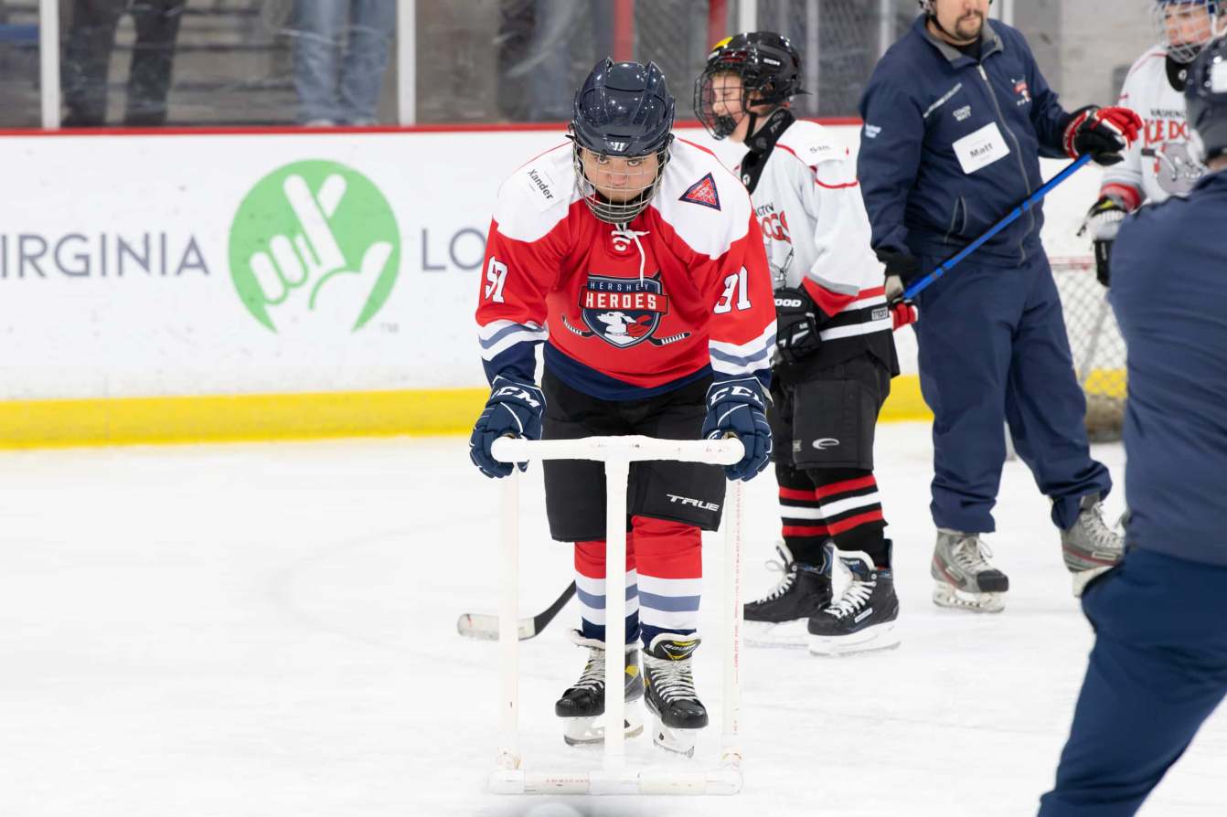 A young player skates with a PVC walker at the American Special Hockey Association clinic