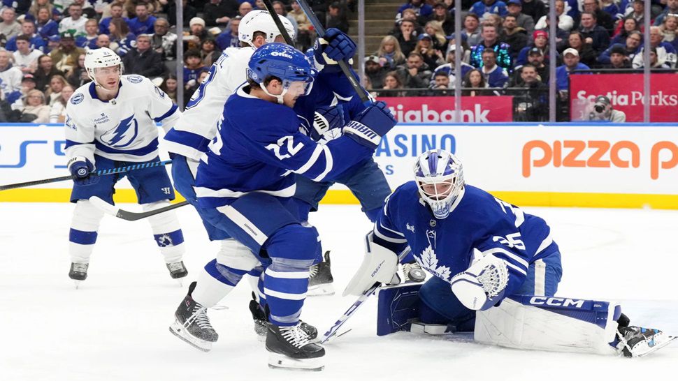 Toronto Maple Leafs goaltender Dennis Hildeby (35) makes a save in front of Tampa Bay Lightning's Jake Guentzel (59) and Leafs defenseman Jake McCabe (22) during the first period of an NHL hockey game in Toronto, Monday, Dec. 8, 2025. (Chris Young/The Canadian Press via AP)