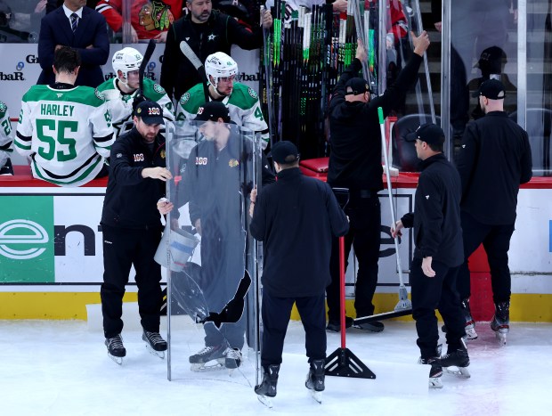 Broken glass is carried away as new glass is prepared to be installed in front of the Dallas Stars bench in the second period of a game between the Stars and the Chicago Blackhawks at the United Center in Chicago on Jan. 1, 2026. (Chris Sweda/Chicago Tribune)