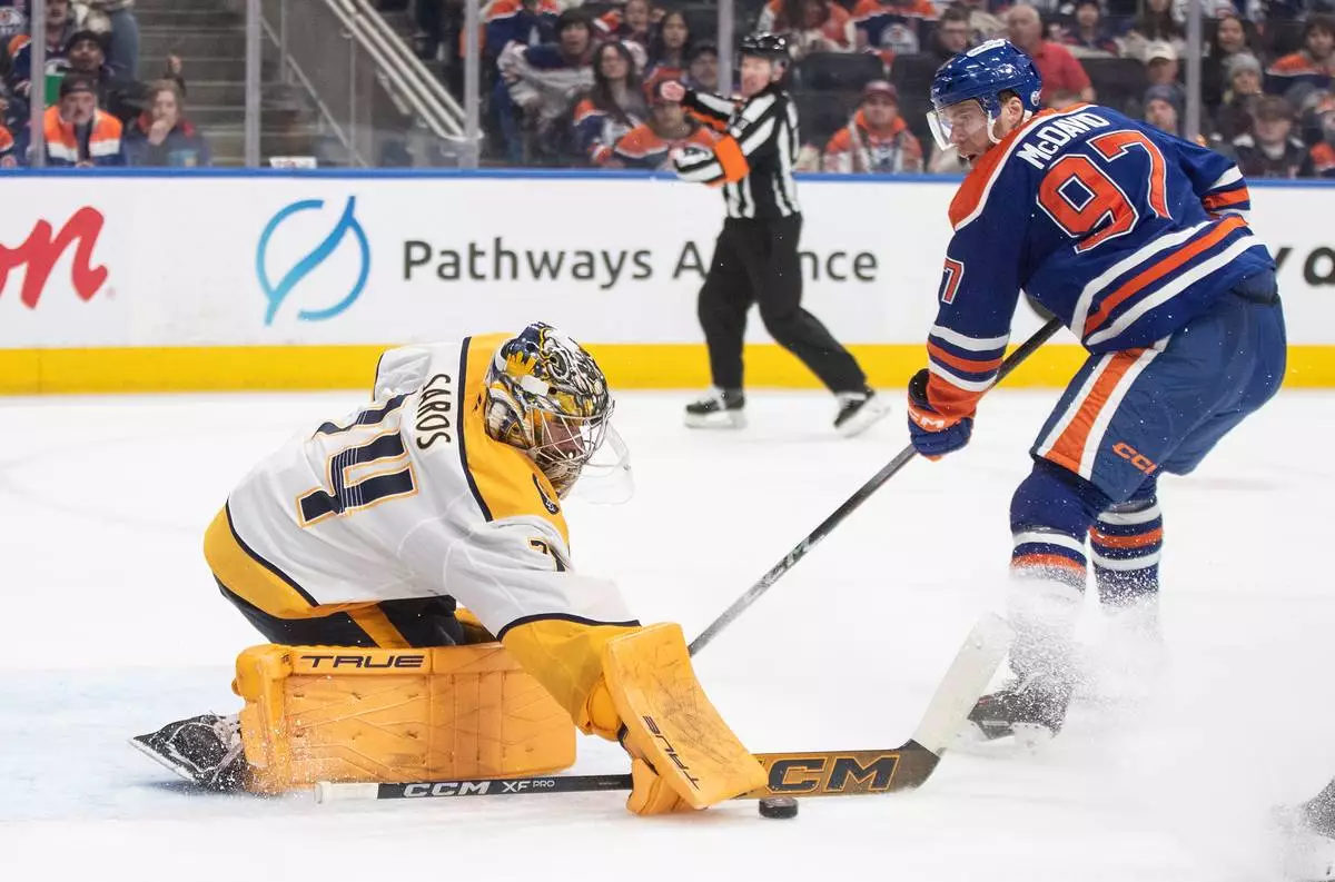 Nashville Predators goalie Juuse Saros (74) makes a save against Edmonton Oilers' Connor McDavid (97) during second period NHL action, in Edmonton, Alberta, on Tuesday, Jan. 6, 2026. (Jason Franson/The Canadian Press via AP)