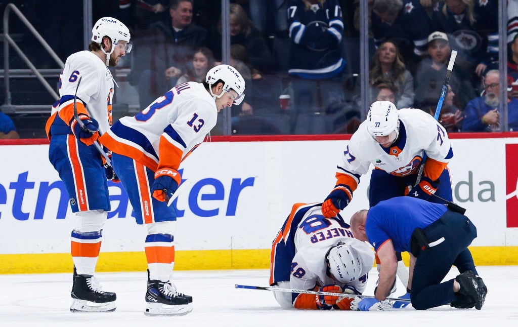 Matthew Schaefer is tended to by a trainer and some teammates  after a Winnipeg goal during the first period of the Islanders' 5-4 road loss to the Jets on Jan. 13, 2025.