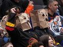 Vancouver Canucks fans wear paper bags on their heads during the third period of a 6-0 loss to the Edmonton Oilers during an NHL hockey game, in Vancouver, on Saturday, Jan. 17, 2026.