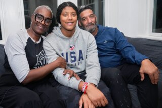Laila Edwards, center, the first Black woman to suit up for Team USA women's Olympic hockey, poses for a photo with her parents, Charone Gray-Edwards, left, and Robert Edwards, right, in her childhood home in Cleveland Heights, Ohio, Wednesday, Nov. 5, 2025. (AP Photo/Sue Ogrocki)