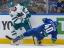 San Jose Sharks' Collin Graf (51) checks Vancouver Canucks' Elias Pettersson (40) during the first period of an NHL hockey game in Vancouver, on Tuesday, January 27, 2026.