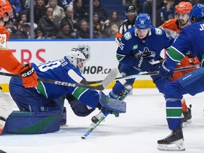 Vancouver Canucks goalie Nikita Tolopilo (60) makes the save as Elias Pettersson (25) and Anaheim Ducks' Chris Kreider (20) watch during the second period