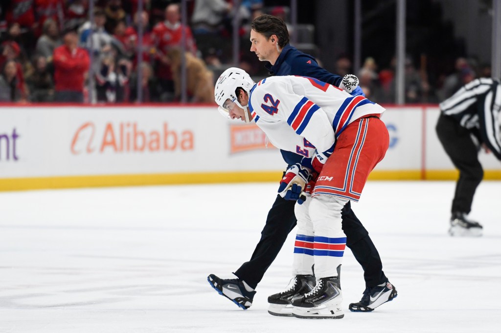 New York Rangers center Noah Laba (42) skates of ice with a trainer after an injury during the second period against the Washington Capitals at Capital One Arena. 