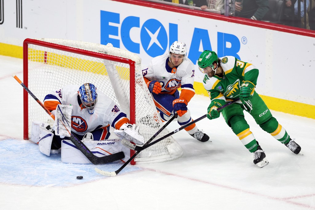 New York Islanders goalie Ilya Sorokin (#30) and player Mathew Barzal (#13) defend the goal against Minnesota Wild player Ryan Hartman (#38).