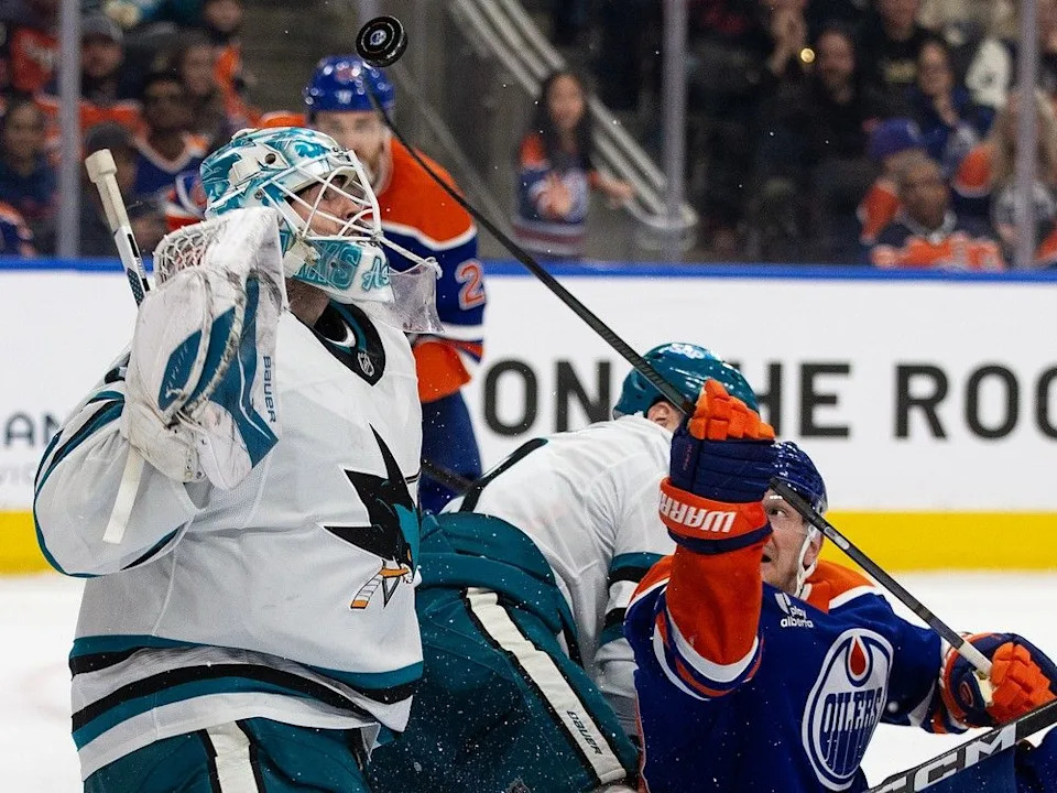 The Edmonton Oilers’ Zach Hyman (18) battles for a loose puck with the San Jose Sharks’ goalie Yaroslav Askarov (30) during third period NHL action at Rogers Place, in Edmonton Thursday Jan. 29, 2026. The Oilers won 4-3 in overtime.
