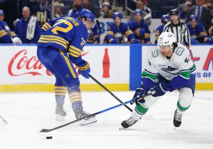 Jan 6, 2026; Buffalo, New York, USA; Vancouver Canucks left wing Kiefer Sherwood (44) takes the puck from Buffalo Sabres center Tage Thompson (72) during the second period at KeyBank Center.
