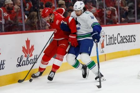 Jan 8, 2026; Detroit, Michigan, USA; Detroit Red Wings left wing James van Riemsdyk (21) and Vancouver Canucks left wing Kiefer Sherwood (44) battle for the puck in the first period at Little Caesars Arena.