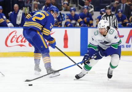 Jan 6, 2026; Buffalo, New York, USA; Vancouver Canucks left wing Kiefer Sherwood (44) takes the puck from Buffalo Sabres center Tage Thompson (72) during the second period at KeyBank Center.