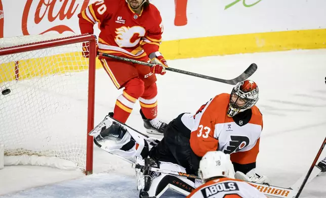 Philadelphia Flyers goalie Samuel Ersson, right, lets in a goal as Calgary Flames' Ryan Lomberg looks on during third period NHL hockey action in Calgary on Wednesday, Dec. 31, 2025. (Jeff McIntosh/The Canadian Press via AP)