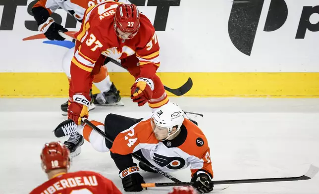 Philadelphia Flyers' Nick Seeler, right, is checked by Calgary Flames' Yan Kuznetsov during second period NHL hockey action in Calgary on Wednesday, Dec. 31, 2025. (Jeff McIntosh/The Canadian Press via AP)