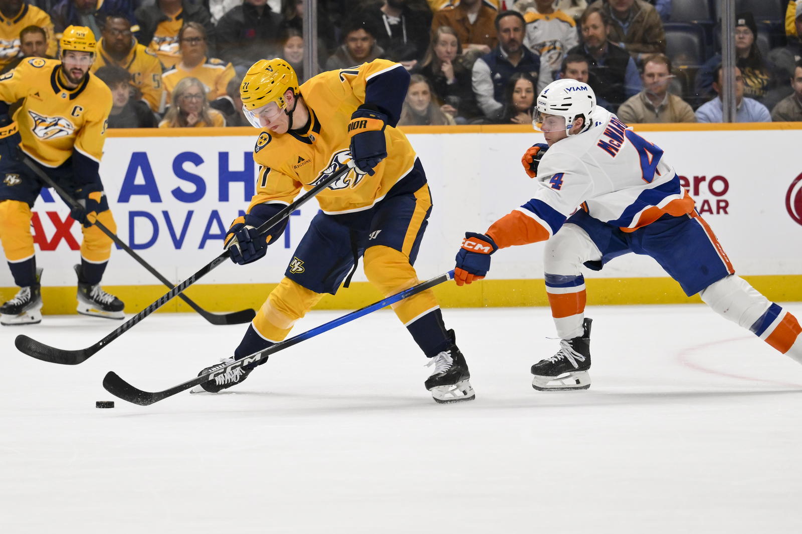 Jan 8, 2026; Nashville, Tennessee, USA; New York Islanders defenseman Cole McWard (4) and Nashville Predators right wing Matthew Wood (71) battle for the puck during the first period at Bridgestone Arena. Mandatory Credit: Steve Roberts-Imagn Images