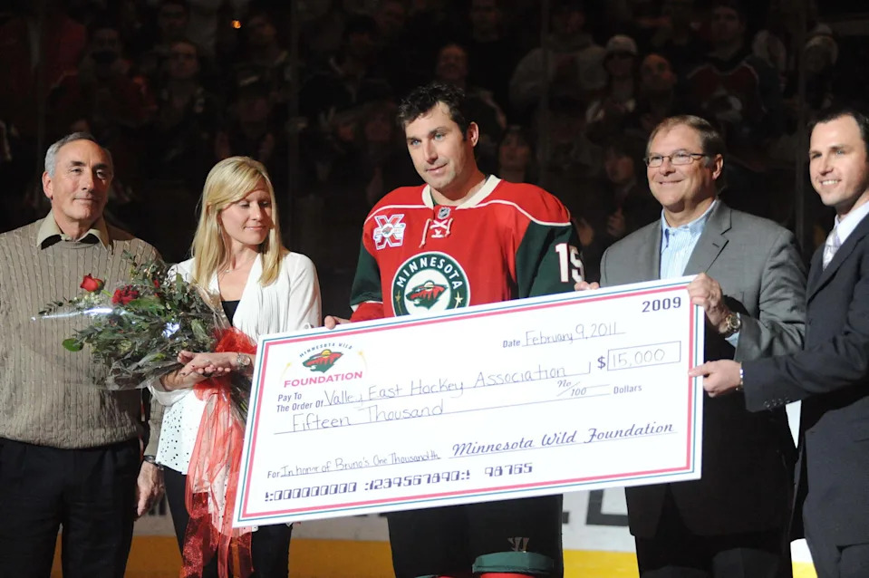 Feb 9, 2011; St. Paul, MN USA; Minnesota Wild forward Andrew Brunette (15) with his wife Laurie Brunette (second left) and father Dan Brunette (left) is presented with a silver hockey stick for his 1000th game played last week before the game against the Colorado Avalanche at Xcel Energy Center. Mandatory Credit: Marilyn Indahl-Imagn Images