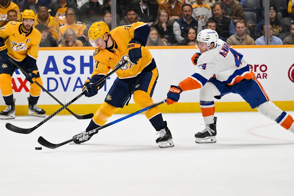 Jan 8, 2026; Nashville, Tennessee, USA; New York Islanders defenseman Cole McWard (4) and Nashville Predators right wing Matthew Wood (71) battle for the puck during the first period at Bridgestone Arena. Mandatory Credit: Steve Roberts-Imagn Images