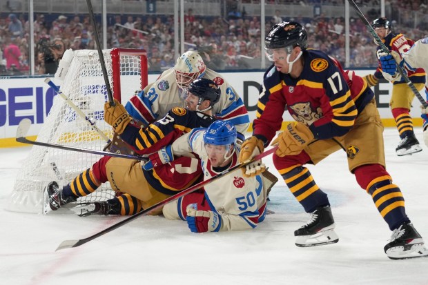 Florida Panthers center Sam Reinhart (13) and New York Rangers left wing Will Cuylle (50) fall into New York Rangers goaltender Igor Shesterkin (31) during the first period of the NHL Winter Classic outdoor hockey game, Friday, Jan. 2, 2026, in Miami. (AP Photo/Lynne Sladky)