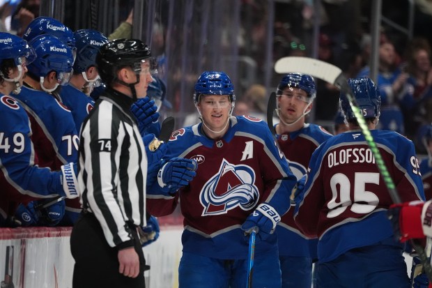 Colorado Avalanche center Nathan MacKinnon (29) is congratulated as he passes the team box after scoring a goal in the second period of an NHL hockey game Monday, Jan. 19, 2026, in Denver. (AP Photo/David Zalubowski)