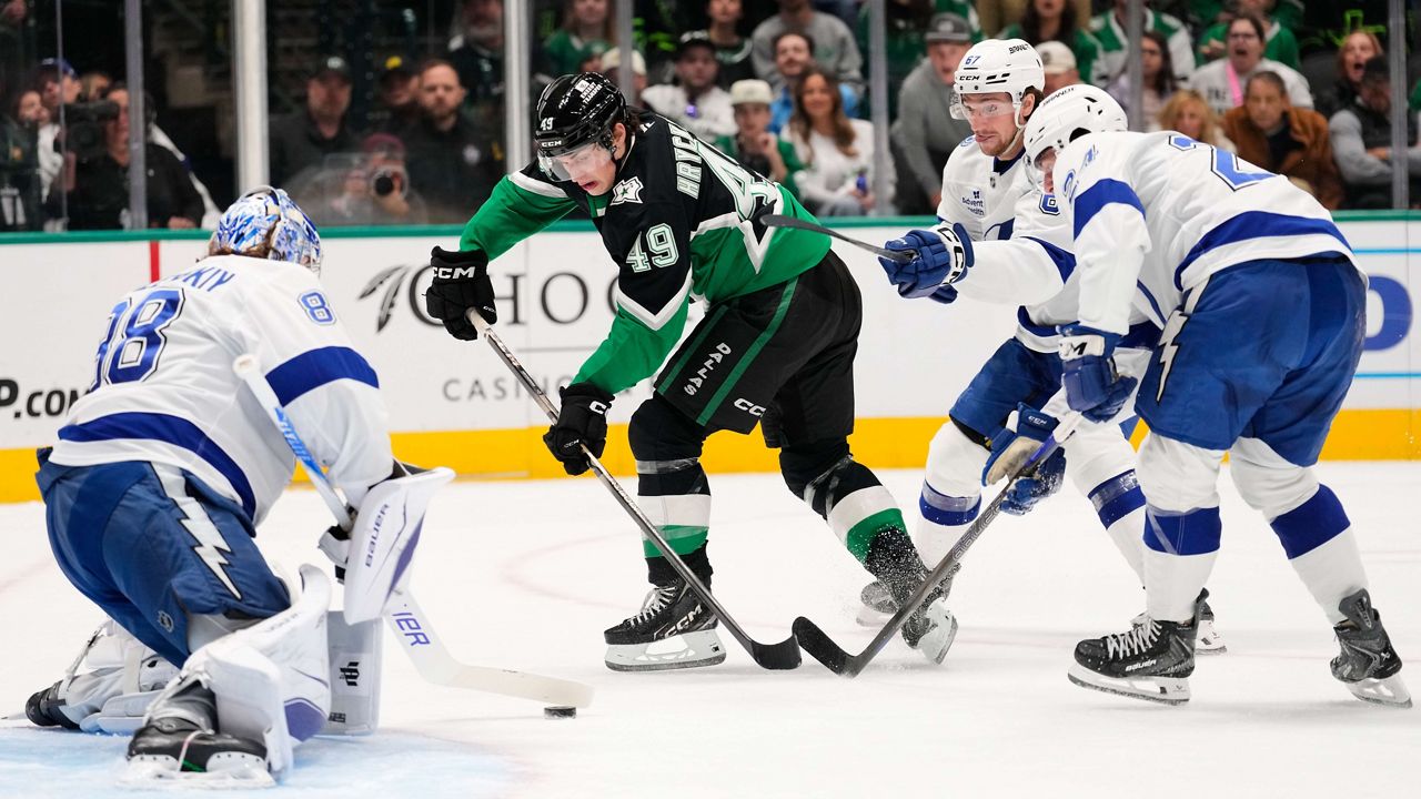 Dallas Stars center Justin Hryckowian (49) takes a shot as Tampa Bay Lightning goaltender Andrei Vasilevskiy, left, Declan Carlile, rear, and Maxwell Crozier (24) defend in the first period of an NHL hockey game in Dallas, Sunday, Jan. 18, 2026. (AP Photo/Tony Gutierrez)