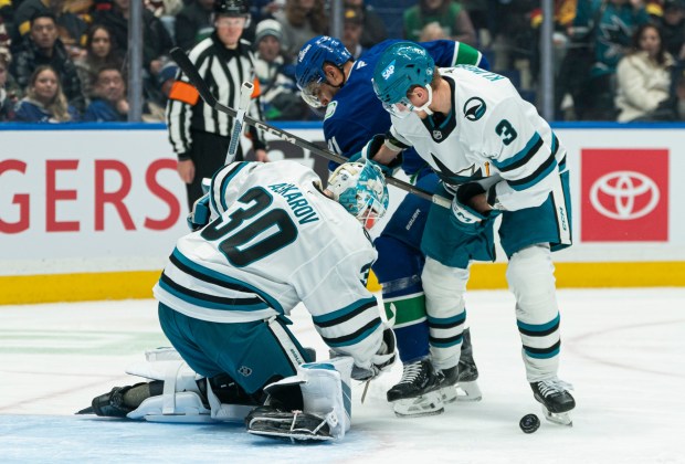 VANCOUVER, CANADA - DECEMBER 27: Goalie Yaroslav Askarov #30 of the San Jose Sharks looks to cover up the loose puck while John Klingberg #3 ties up Evander Kane #91 of the Vancouver Canucks during the first period of NHL action at Rogers Arena on December 27, 2025 in Vancouver, Canada. (Photo by Rich Lam/Getty Images)