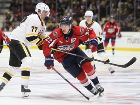 Windsor Spitfires' Jean-Cristoph Lemieux (22) squeezes past Sarnia Sting's Hughston Hurt (77) at Progressive Auto Sales Arena in Sarnia, Ont., on Friday, Sept. 19, 2025. Mark Malone/Chatham Daily News/Postmedia Network