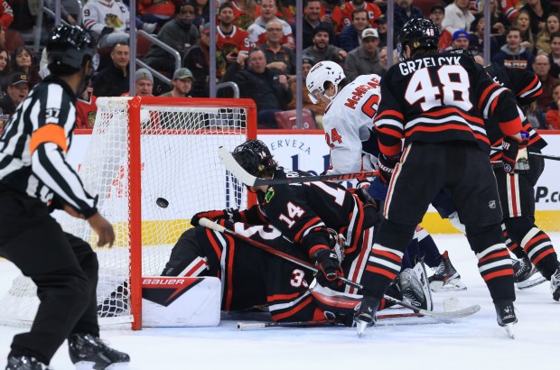 The puck flies into the net past Blackhawks goaltender Drew Commesso (33) for a goal by Capitals right wing Justin Sourdif in the second period at the United Center on Jan. 9, 2026, in Chicago. (John J. Kim/Chicago Tribune)