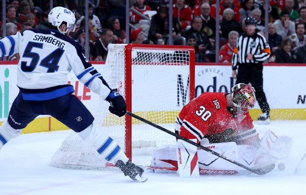 Chicago Blackhawks goaltender Spencer Knight (30) blocks a shot by Winnipeg Jets defenseman Dylan Samberg (54) in the second period of a game at the United Center in Chicago on Jan. 19, 2026. (Chris Sweda/Chicago Tribune)