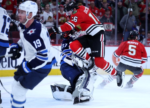 Chicago Blackhawks center Jason Dickinson (16) collides with Winnipeg Jets goaltender Connor Hellebuyck (37) in the third period of a game at the United Center in Chicago on Jan. 19, 2026. (Chris Sweda/Chicago Tribune)