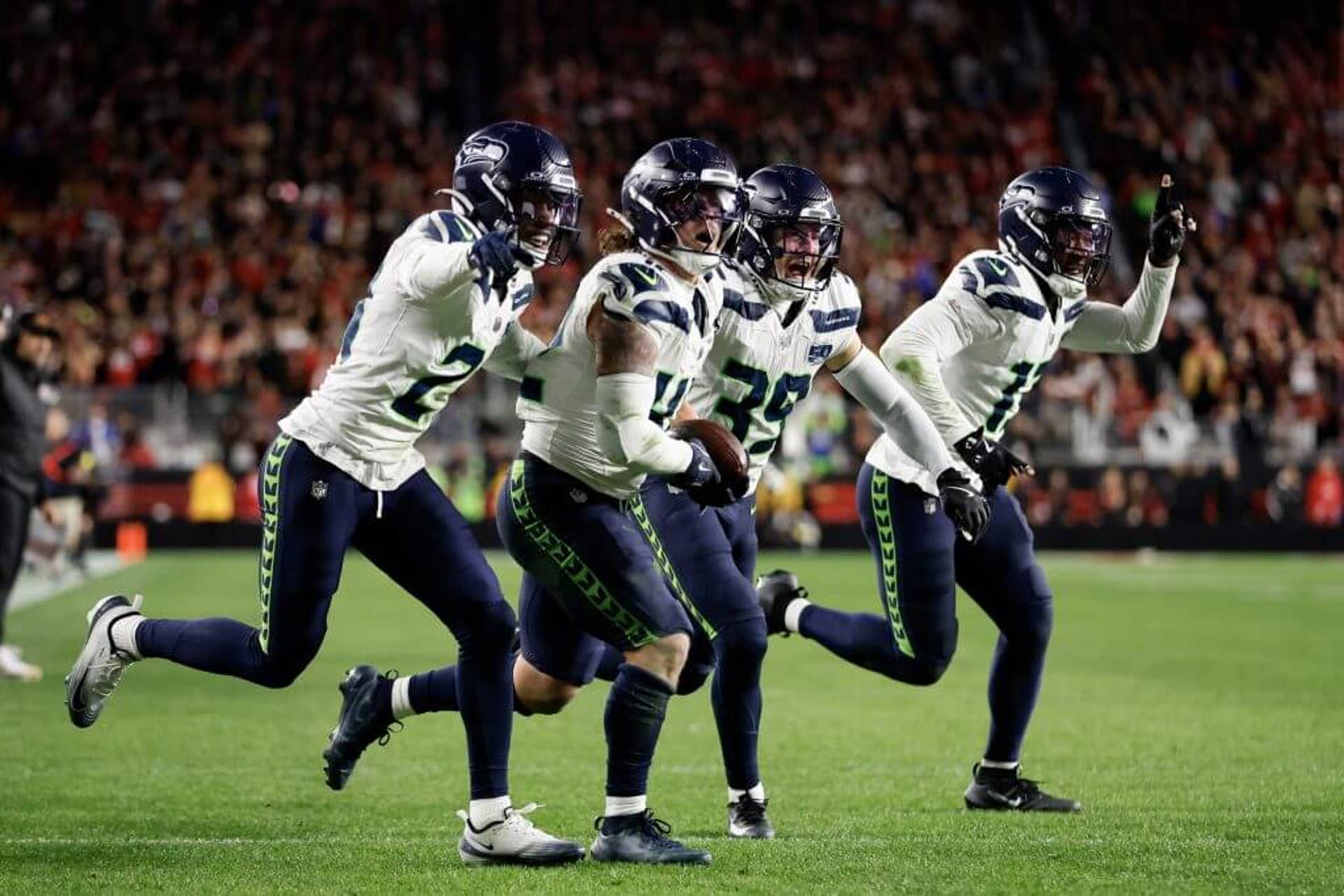 Seattle's Drake Thomas (42) carries the football and runs in celebration with with teammates after an interception against the San Francisco 49ers.