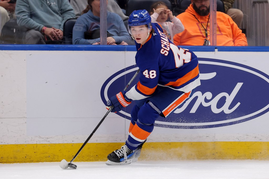 A New York Islanders player #48, likely Simon Holmstrom, skates with his stick on the ice during a game against the Buffalo Sabres.