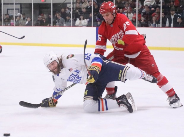 Detroit Red Wing alumni Darren McCarty battles for position with an unidentified member of the Lincoln Park team during Saturday's fundraiser game. (CONSTANCE YORK--For The News-Herald)
