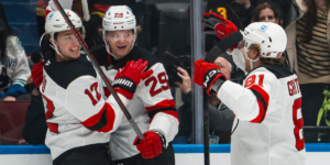 Cody Glass(12), Lenni Hameenaho(29) and Arseni Gritsyuk(81) celebrate Hameenaho's first career NHL goal in the first period of the New Jersey Devils' game against the Vancouver Canucks.