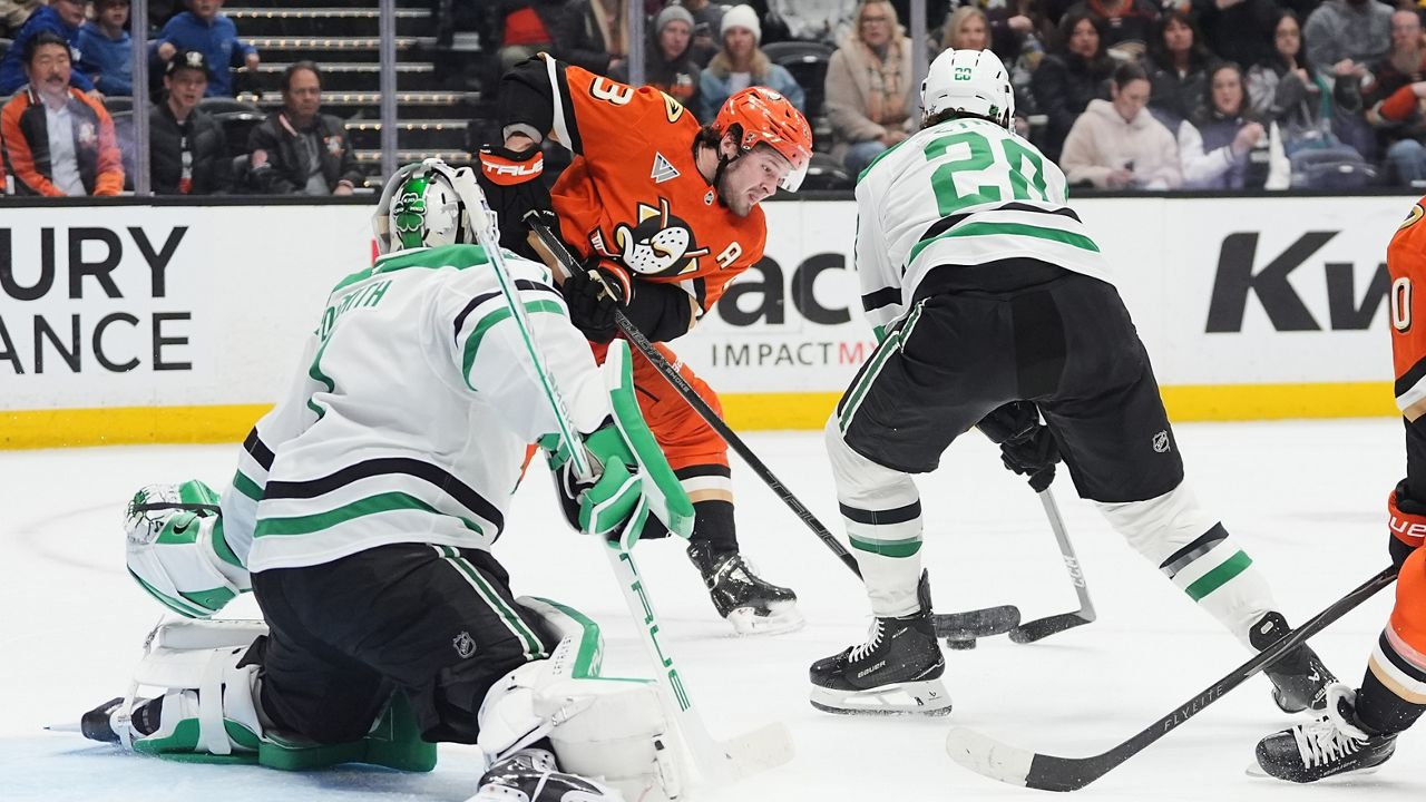 Anaheim Ducks center Mason McTavish, center, shoots as Dallas Stars goaltender Casey DeSmith, left, and defenseman Alexander Petrovic defend during the first period of an NHL hockey game Tuesday, Jan. 13, 2026, in Anaheim, Calif. (AP Photo/Gregory Bull)