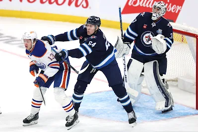 Winnipeg Jets defenseman Logan Stanley checks a player in front of the net