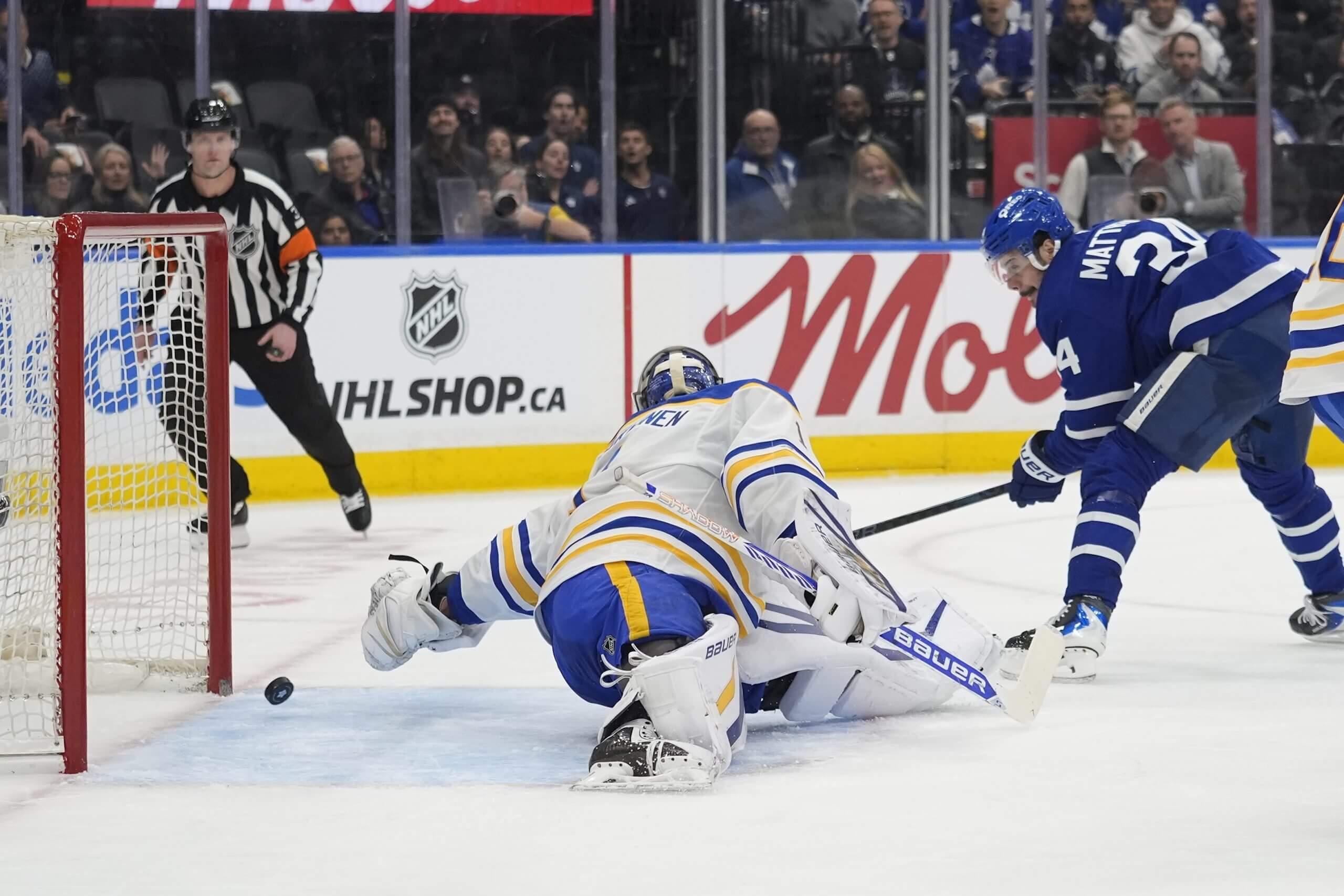 Sabres goalie Ukka-Pekka Luukkonen reaches behind himself to try to save a puck shot by Auston Matthews before it bounces into the net.