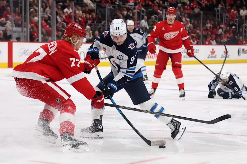 Cole Perfetti of the Winnipeg Jets tries to get a shot off next to Simon Edvinsson of the Detroit Red Wings during the first period at Little Caesars Arena in Detroit on Dec. 31, 2025.