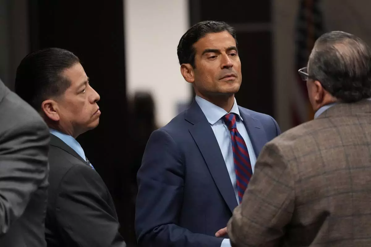Former Uvalde school district police officer Adrian Gonzales, left, stands with his attorney Nico LaHood during a break in his trial at the Nueces County Courthouse in Corpus Christi, Texas, Tuesday, Jan. 6, 2026. (AP Photo/Eric Gay, Pool)