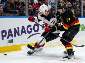 Two NHL hockey players chase the puck.