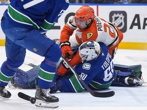 Anaheim Ducks' Ryan Poehling (25) crashes into Vancouver Canucks goalie Nikita Tolopilo (60) during the first period