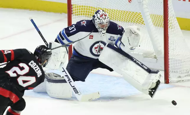 Winnipeg Jets goaltender Connor Hellebuyck (37) makes a save on a shot by Ottawa Senators' Dylan Cozens (24) during the second period of an NHL hockey game in Ottawa, Ontario, on Saturday, Jan. 3, 2026. (Patrick Doyle/The Canadian Press via AP)