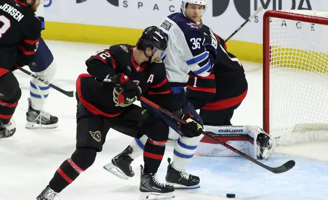 Ottawa Senators' Thomas Chabot, center, and Winnipeg Jets' Morgan Barron (36) battle for the puck during the first period of an NHL hockey game in Ottawa, Ontario, Saturday, Jan. 3, 2026. (Patrick Doyle/The Canadian Press via AP)