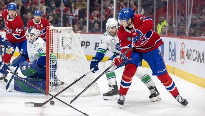  Montreal Canadiens’ Noah Dobson passes the puck from behind the Vancouver Canucks’ net while under pressure from Jake DeBrusk during the first period at the Bell Centre in Montreal on Monday January 12, 2026.