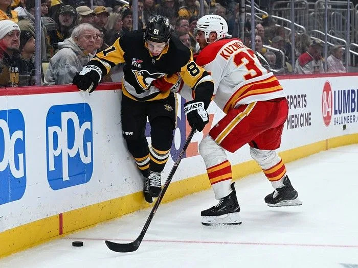  Ben Kindel of the Pittsburgh Penguins goes for the puck against Yan Kuznetsov of the Calgary Flames in the third period during the game at PPG PAINTS Arena on Jan. 10, 2026, in Pittsburgh, Pennsylvania.
