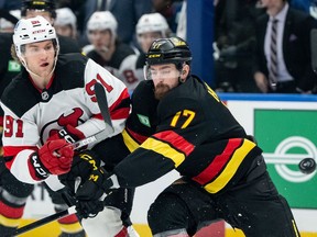 Two NHL hockey players grapple for position on the ice.