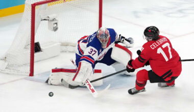 Feb 22, 2026; Milan, Italy; Connor Hellebuyck of the United States battles for the puck against Macklin Celebrini of Canada during the men's ice hockey gold medal game during the Milano Cortina 2026 Olympic Winter Games at Milano Santagiulia Ice Hockey Arena. Mandatory Credit: James Lang-Imagn Images