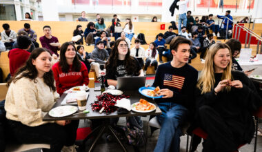 A group of students sit at a table for a watch party of the gold medal hockey game.